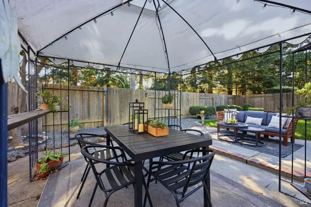 a view of a patio with table and chairs potted plants and a large tree