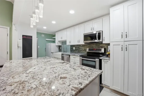 a kitchen with stainless steel appliances granite countertop a refrigerator stove microwave and sink