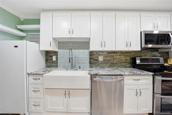 a kitchen with kitchen island granite countertop a sink stainless steel appliances and white cabinets