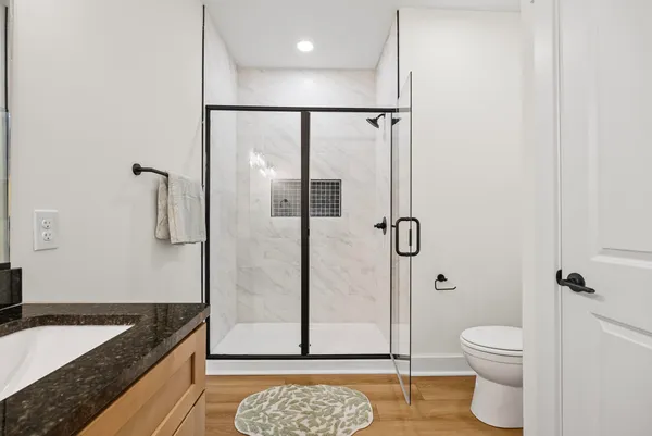 a bathroom with a granite countertop sink a toilet and shower