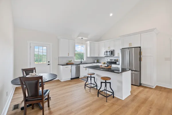 a kitchen with a dining table chairs and refrigerator