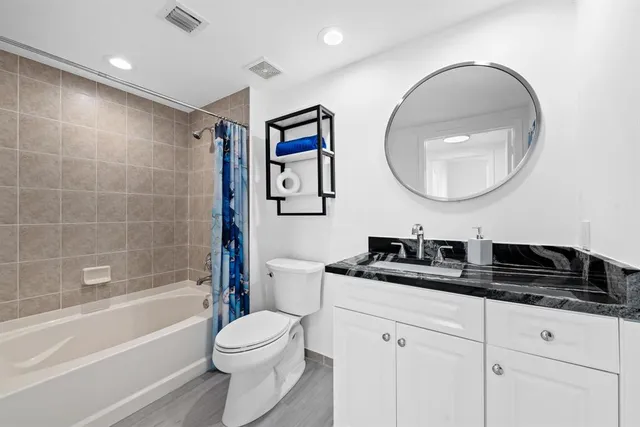 a bathroom with a granite countertop sink a toilet and a bathtub