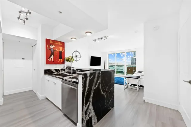 a kitchen with stainless steel appliances a stove top oven a sink a dining table and chairs with wooden floor