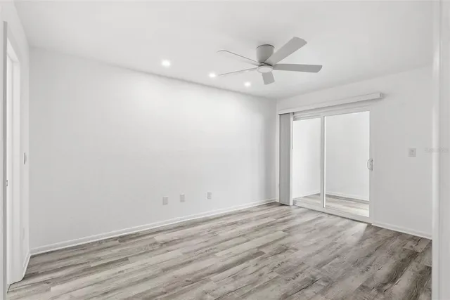 an empty room with wooden floor fan and windows