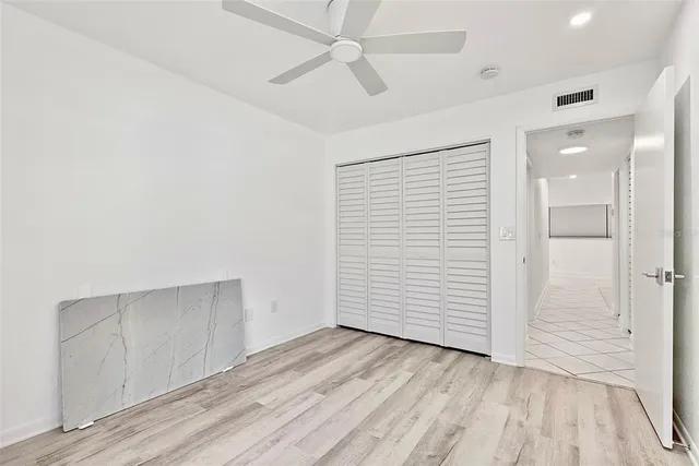 an empty room with wooden floor closet and windows