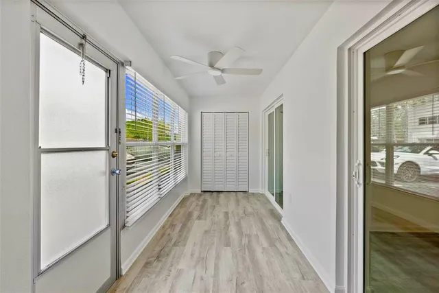 a view of a hallway with wooden floor and a bathroom