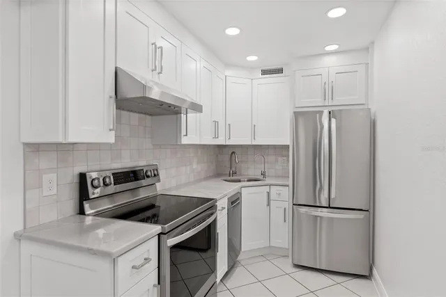 a kitchen with white cabinets and stainless steel appliances