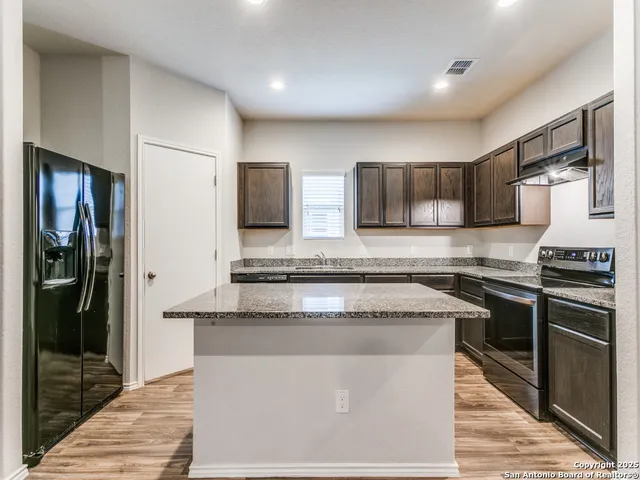 a kitchen with stainless steel appliances granite countertop a stove a refrigerator and a sink
