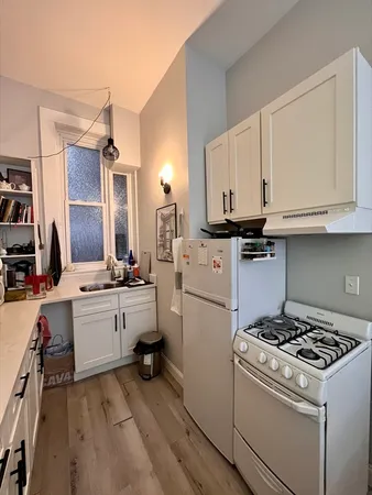 a kitchen with sink a stove and white cabinets