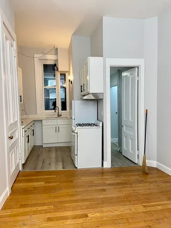 a view of a kitchen with kitchen island wooden floor and stainless steel appliances