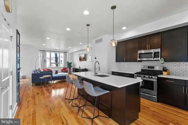 a kitchen with stainless steel appliances granite countertop a refrigerator a sink a stove and a wooden floors