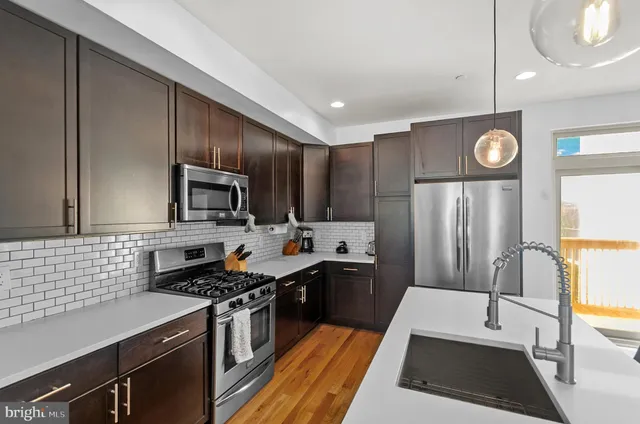 a kitchen with a sink stove and wooden floor