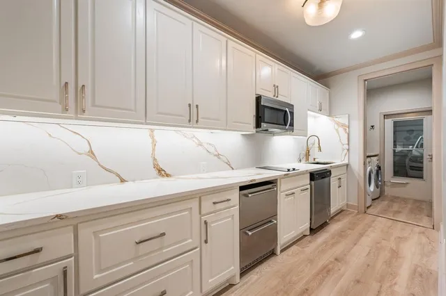 a kitchen with granite countertop white cabinets and stainless steel appliances