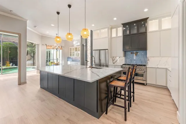 a kitchen with stainless steel appliances kitchen island granite countertop a table chairs and a refrigerator