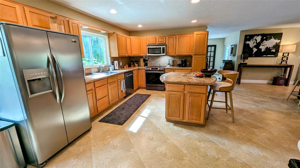 8105 Nutmeg Way Tamarac, FL 33321 - Photo 7 of 28 a kitchen with stainless steel appliances granite countertop a refrigerator a stove a sink dishwasher a refrigerator with a dining table and chairs