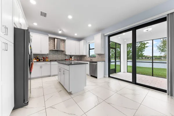a kitchen with granite countertop a refrigerator and white cabinets