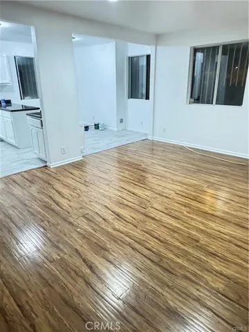 a view of kitchen and empty room with wooden floor