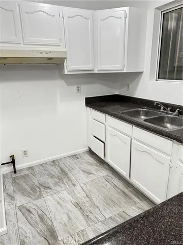 a kitchen with granite countertop white cabinets and sink