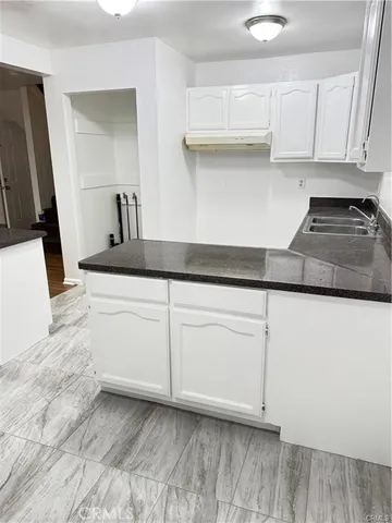 a kitchen with granite countertop white cabinets and a sink