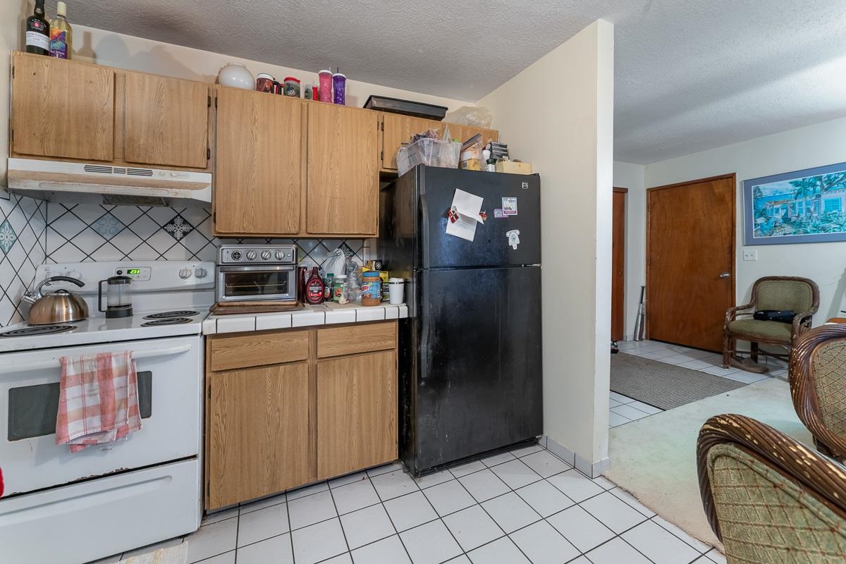 899 Kokomo Road Haiku, HI 96708 - Photo 9 of 26 a kitchen with stainless steel appliances granite countertop a refrigerator and a stove top oven