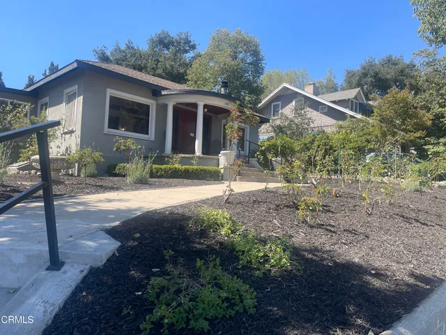 a front view of a house with a yard and potted plants