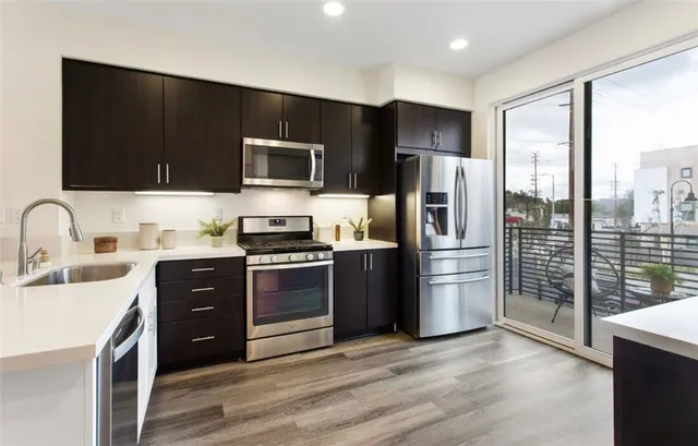 a kitchen with stainless steel appliances a stove refrigerator a sink and a microwave