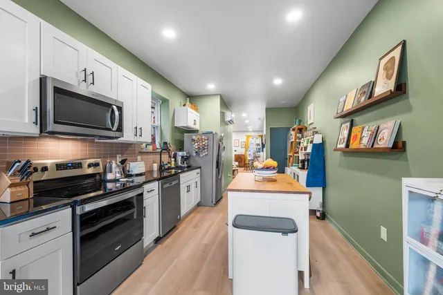 a large kitchen with stainless steel appliances granite countertop a lot of counter space cabinets and a stove