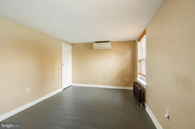 an empty room with wooden floor and windows with curtains