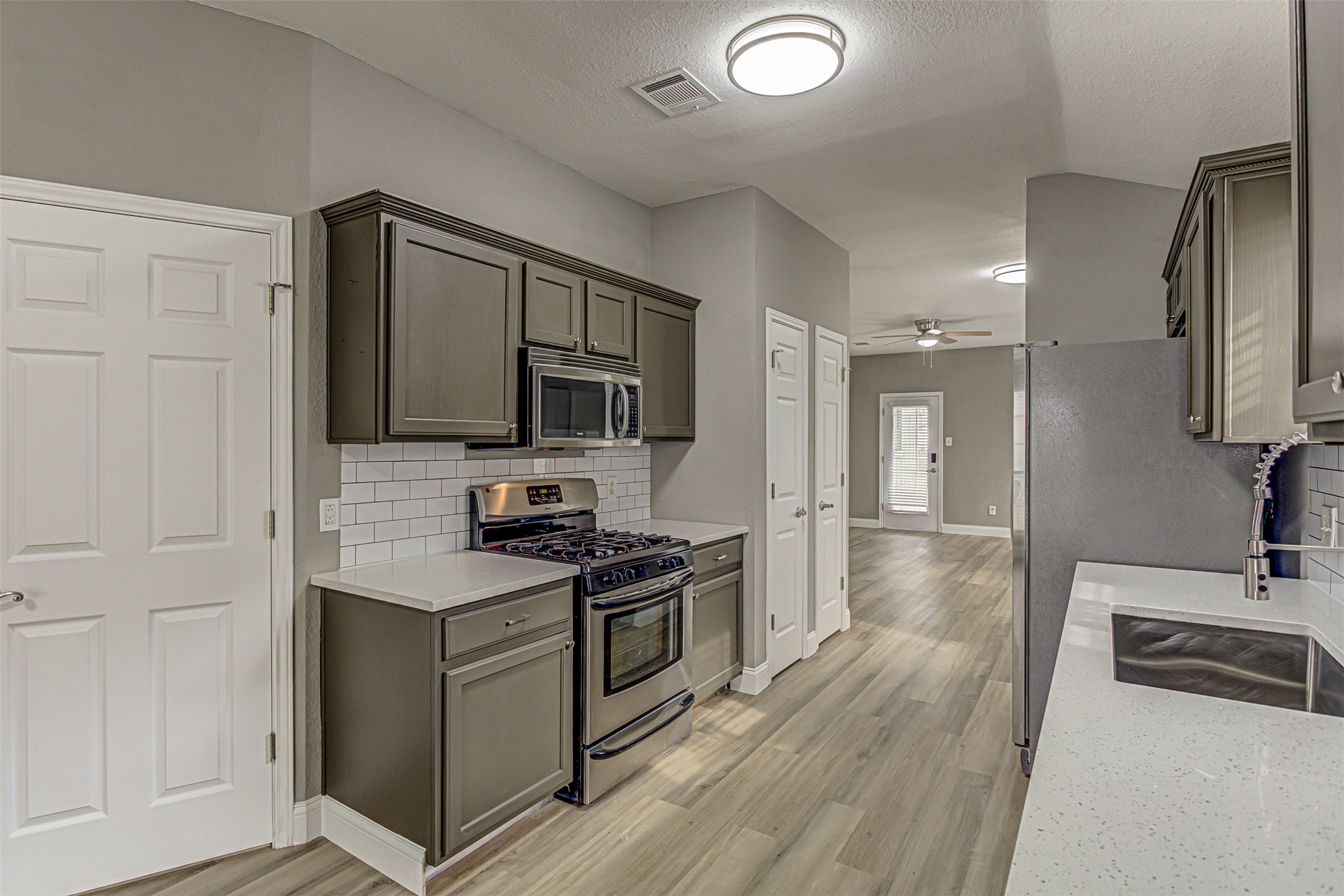 17838 Loch Linnhe Loop Pflugerville, TX 78660 - Photo 9 of 35 a kitchen with stainless steel appliances a sink dishwasher a refrigerator and a stove with wooden floor