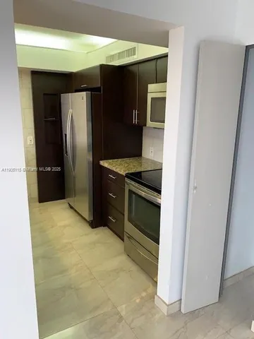a kitchen with stainless steel appliances granite countertop a refrigerator and a stove