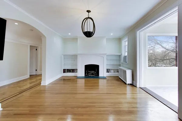 an empty room with wooden floor fireplace and windows