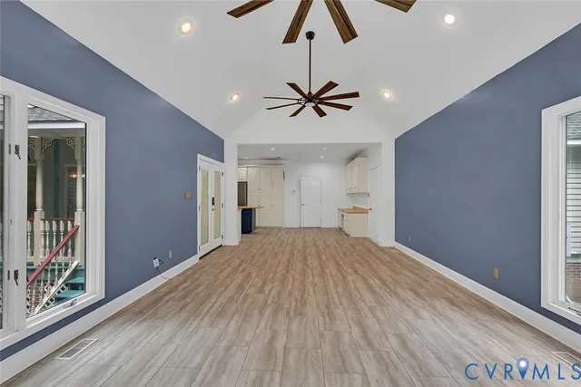 a view of empty room with wooden floor and fan