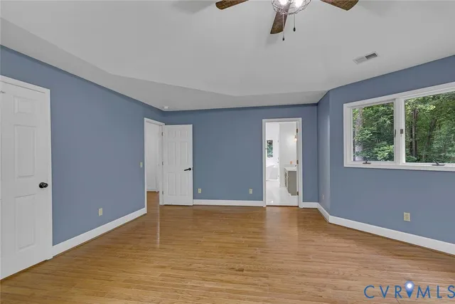 a view of an empty room with window and wooden floor