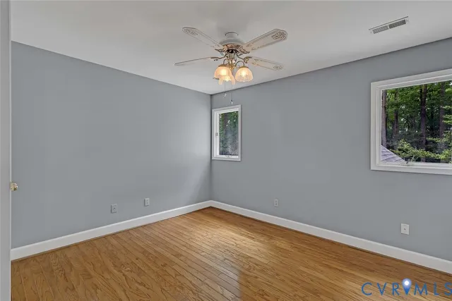 a view of an empty room with window and wooden floor