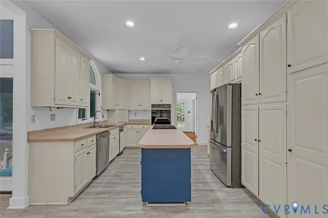a kitchen with stainless steel appliances granite countertop a refrigerator a sink dishwasher and white cabinets with wooden floor