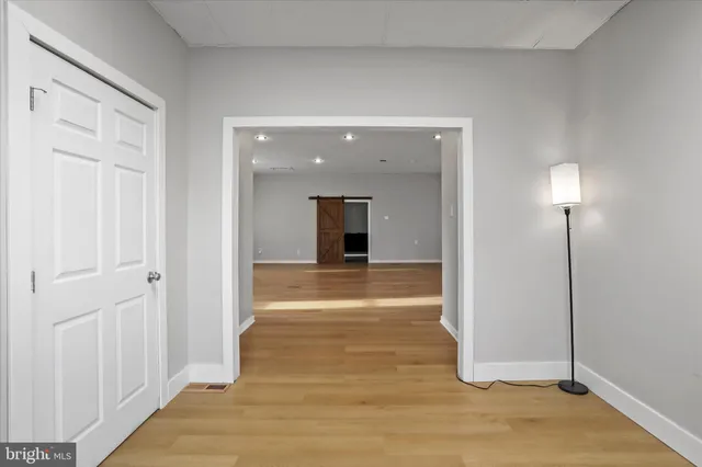 a view of a hallway with wooden floor and a bathroom