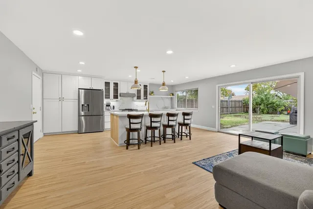 a kitchen with stainless steel appliances granite countertop a dining table chairs refrigerator and sink