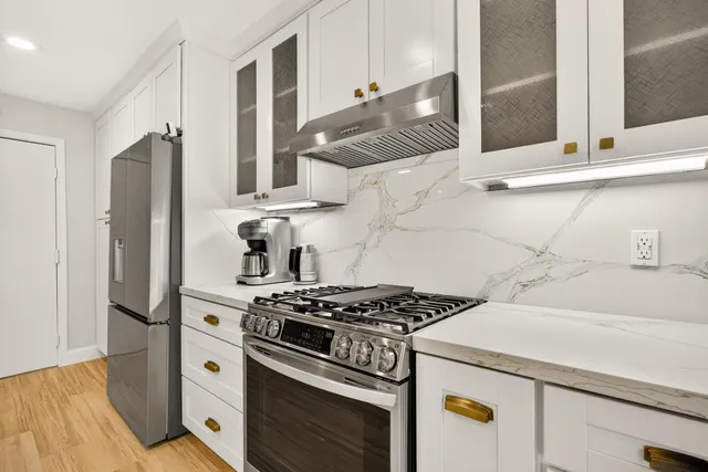 a kitchen with stainless steel appliances granite countertop wooden floors a stove a sink and a refrigerator