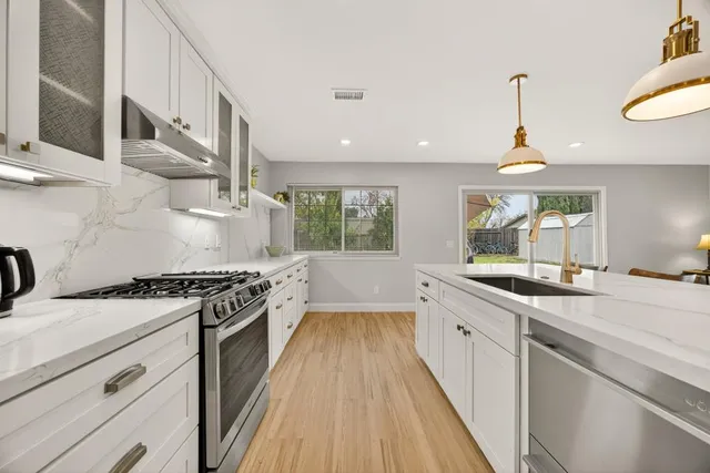 a kitchen with stainless steel appliances white cabinets and a stove top oven