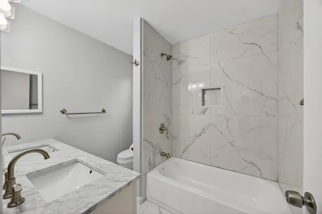 a bathroom with a granite countertop sink a mirror and shower