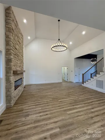 a view of an empty room with wooden floor and a fireplace