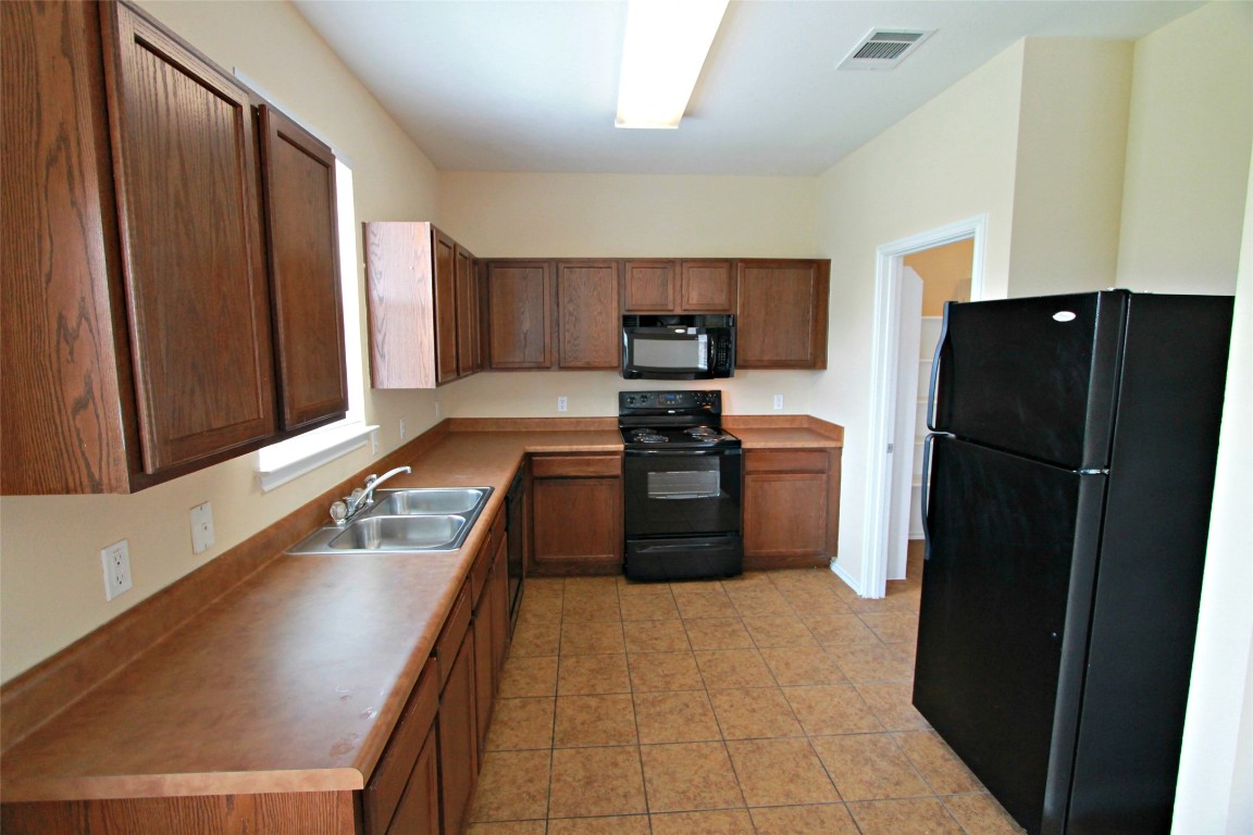 213 Banner Avenue Leander, TX 78641 - Photo 4 of 22 Kitchen featuring black appliances, light countertops, and light tile patterned floors