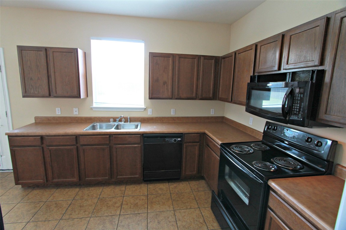 213 Banner Avenue Leander, TX 78641 - Photo 7 of 22 Kitchen featuring black appliances, dark brown cabinetry, and light tile patterned flooring
