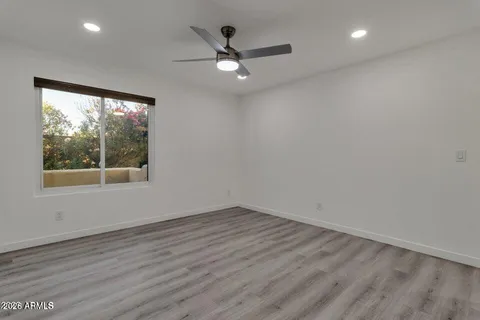 an empty room with wooden floor and ceiling fan