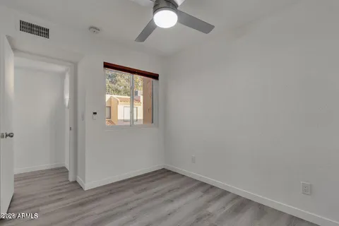 an empty room with wooden floor fan and windows