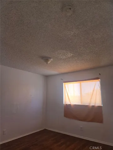 a view of an empty room and wooden floor and a window