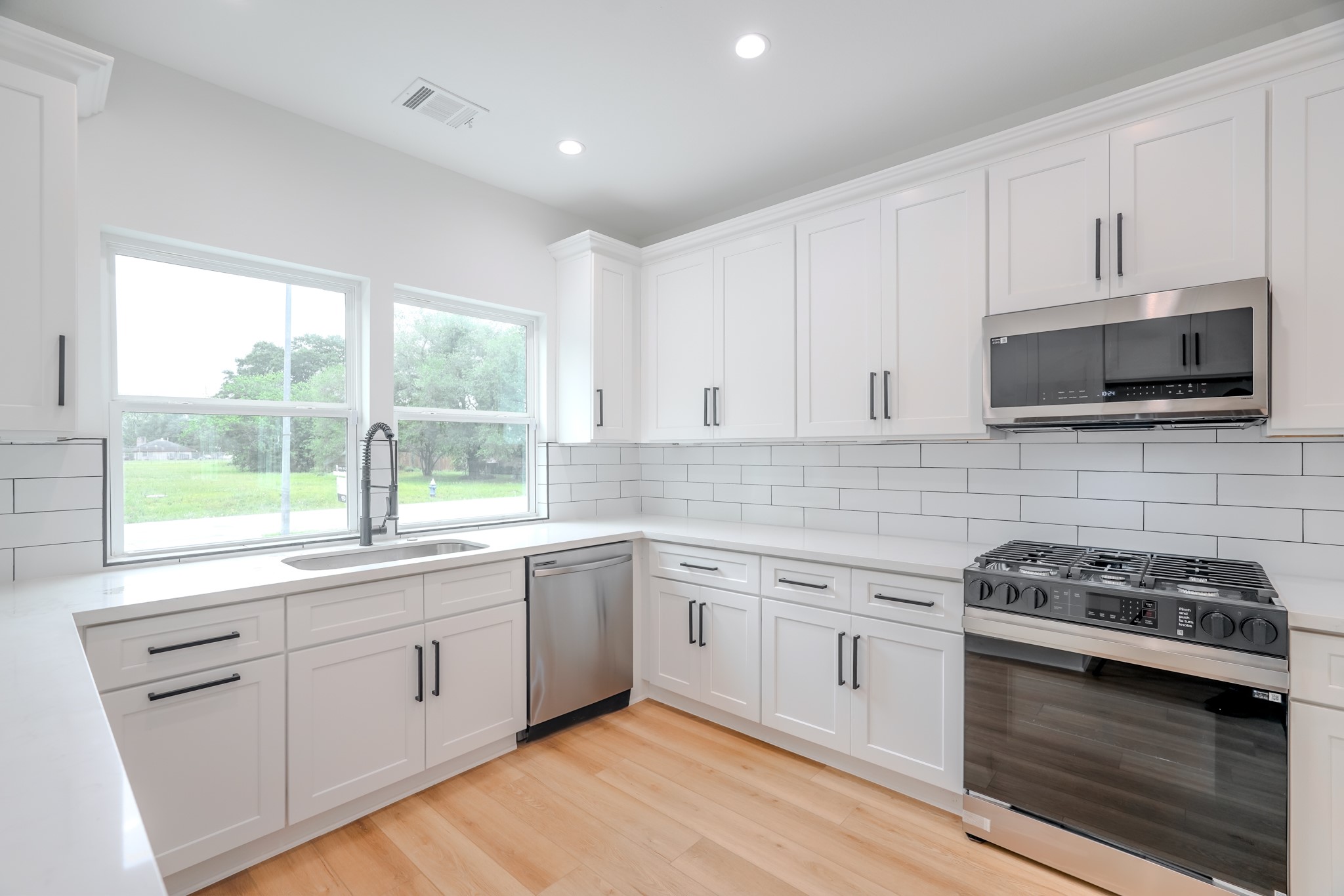7903 Sunnyhill Street Houston, TX 77088 - Photo 7 of 33 a kitchen with white cabinets appliances a sink and a window
