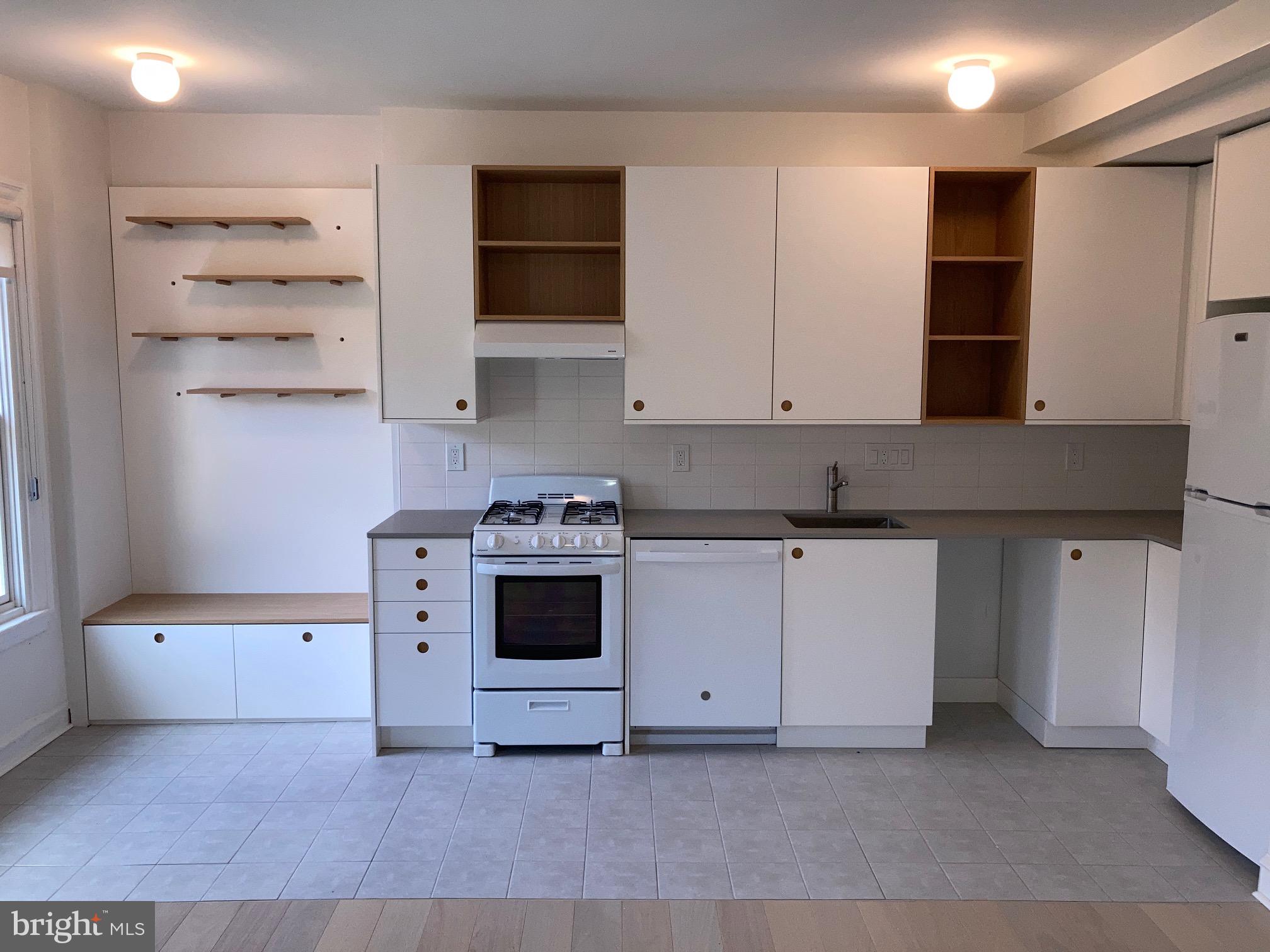 a white kitchen with granite countertop a stove and a sink