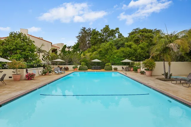 a view of a swimming pool with a lawn chairs under an umbrella