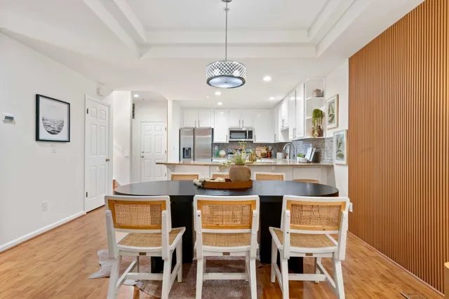 a kitchen with stainless steel appliances granite countertop a dining table chairs refrigerator and microwave